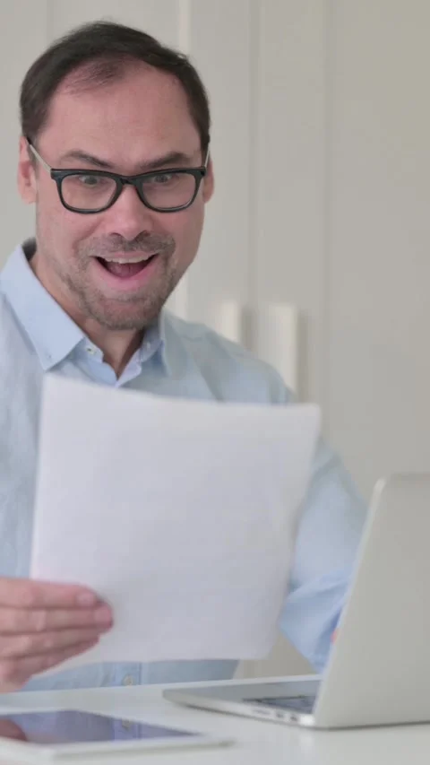 Successful Middle Aged Man Reading Documents while using Laptop, Vertical Video 스톡 동영상 339584776