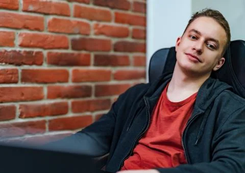 Successful programmer sitting in a comfortable black chair and looking at cam 스톡 사진