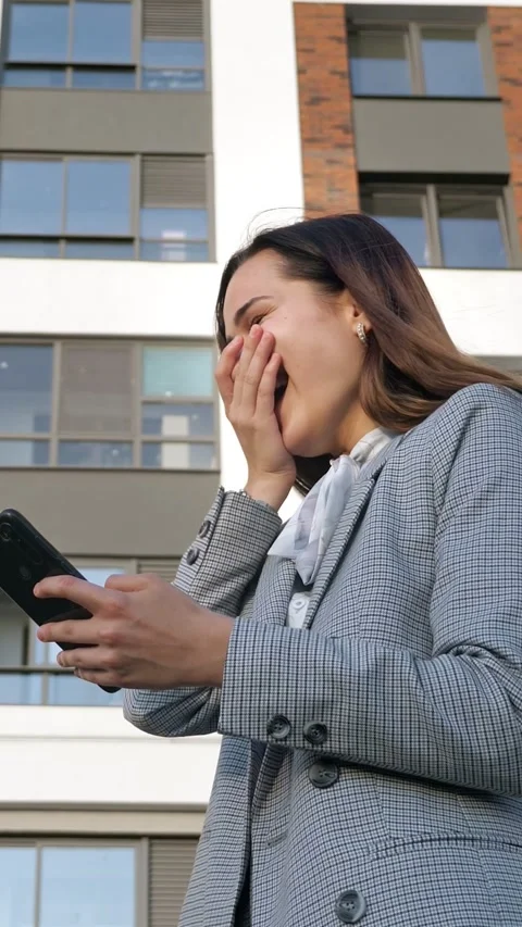 Successful realtor checking smartphone messages and celebrating good news with Stock Footage 341446013