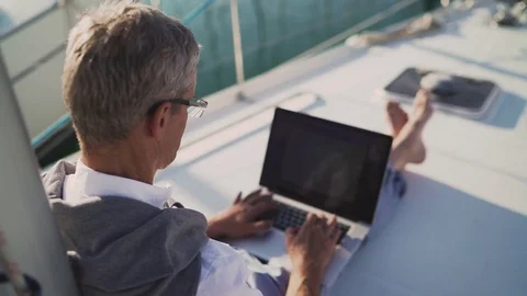 Successful Senior Man Businessman using Laptop on his Yacht at Sunset Видео 80688523