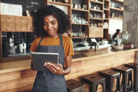 Successful small business owner using digital tablet in her cafe Stock Photos