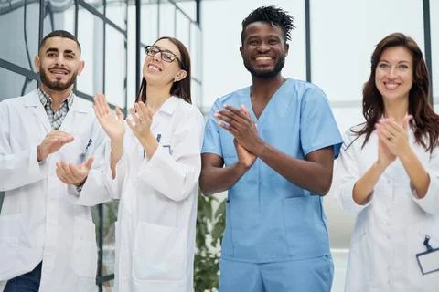 Successful team of different doctors clapping hands Stock Photos
