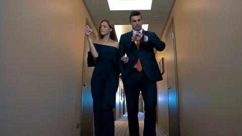 Successful young couple walking down the corridor carpet to meet success Video stock 105970622