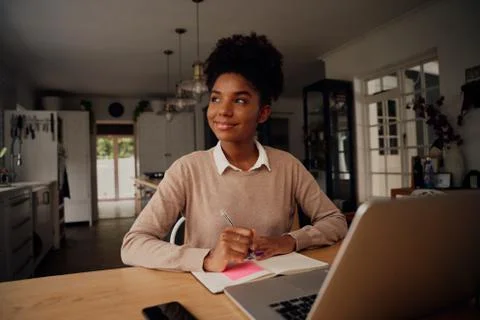 Successful young entrepreneur thinking while writing in diary and using laptop Stock Photos