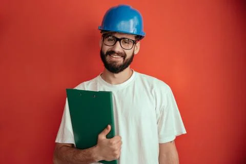 Successful young man engineer in protective helmet and white shirt holding Stock Photos