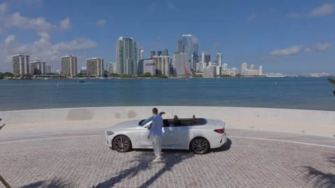 Successful Young Man Getting Out of White Convertible with Miami Skyline Stock Footage 317253359