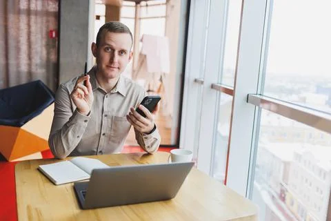Successful young man is sitting at a table in a cafe-restaurant indoors, work Photos