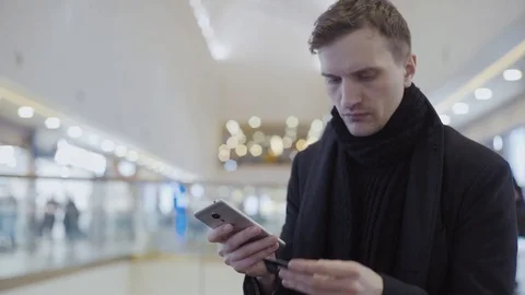 Successful young man using smartphone and plastic card for online transactions Stock Footage 74162138