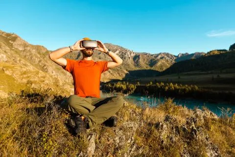 Successful young man, using virtual reality goggles to tour in mountains, on 스톡 사진