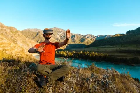Successful young man, using virtual reality goggles to tour in mountains, on Foto stock
