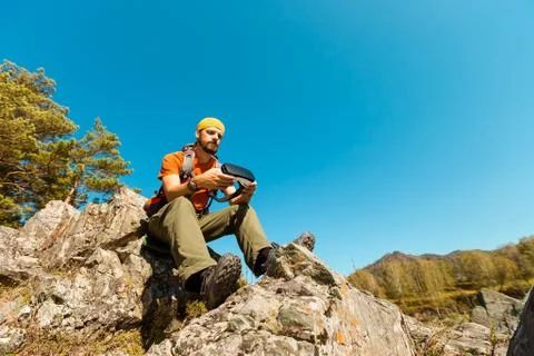 Successful young man, using virtual reality goggles to tour in mountains, on Fotos de archivo