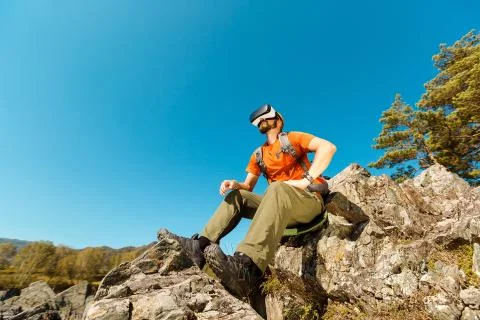 Successful young man, using virtual reality goggles to tour in mountains, on Foto stock
