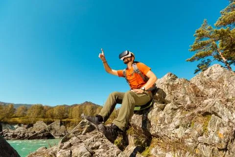 Successful young man, using virtual reality goggles to tour in mountains, on 写真素材