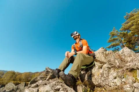 Successful young man using virtual reality goggles tour in mountains on vacation Stock Photos
