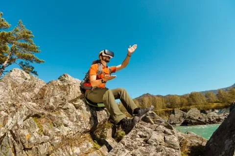 Successful young man using virtual reality goggles tour in mountains on vacation Stock-Fotos