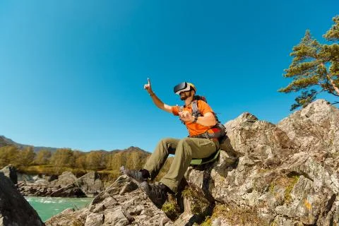 Successful young man using virtual reality goggles tour in mountains on vacation Foto stock