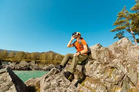 Successful young man using virtual reality goggles tour in mountains on vacation 写真素材