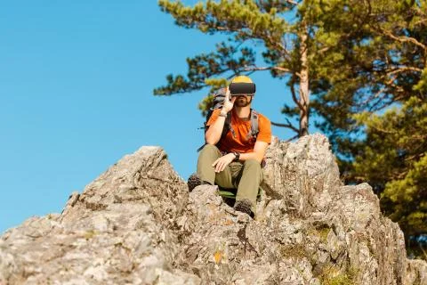 Successful young man, using virtual reality goggles to tour in mountains, on Fotos de archivo