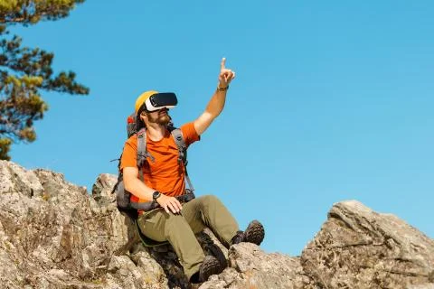 Successful young man, using virtual reality goggles to tour in mountains, on 스톡 사진