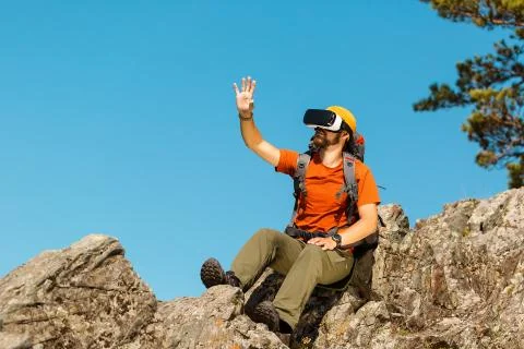 Successful young man, using virtual reality goggles to tour in mountains, on Stock-Fotos