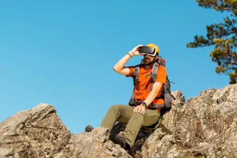 Successful young man, using virtual reality goggles to tour in mountains, on 스톡 사진