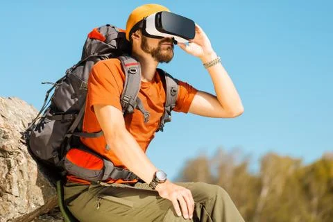 Successful young man, using virtual reality goggles to tour in mountains, on Stock Photos
