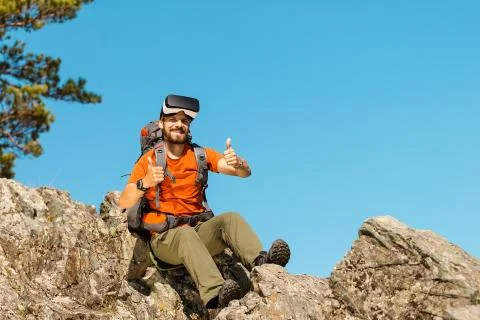 Successful young man, using virtual reality goggles to tour in mountains, on Stock Photos