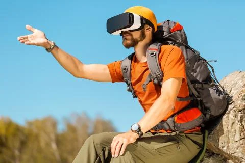 Successful young man, using virtual reality goggles to tour in mountains, on Stock-Fotos