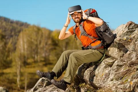 Successful young man, using virtual reality goggles to tour in mountains, on Stock-Fotos