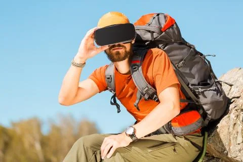 Successful young man, using virtual reality goggles to tour in mountains, on 写真素材