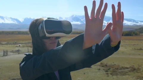 Successful young woman, using virtual reality goggles to tour in mountains, on Видео 102479885