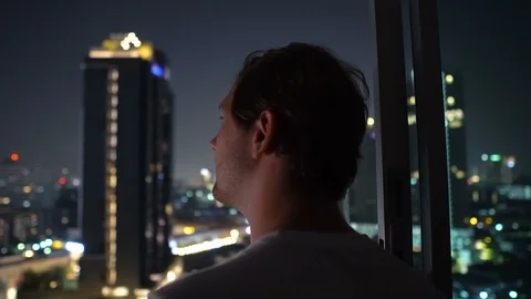 Sucessful Young Man Looking at City Skyline From High Rise Apartment Building Stock Footage 124453388