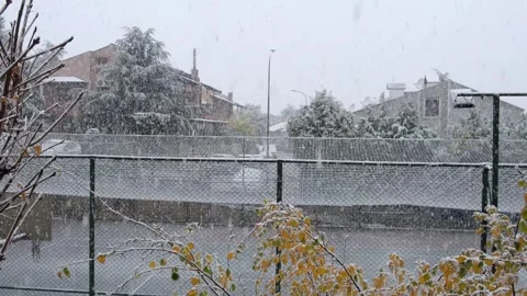 Sudden Snow Dump: Cascading Snow from Fenced Basketball Court Stock Footage 293513702