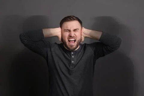 Suffering from hallucination. Man screaming and closing ears not to hear sh.. Stock-Fotos