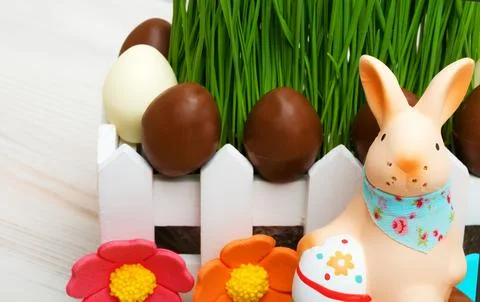 Sugar bunny and Easter chocolate eggs on green grass background. Stock Photos