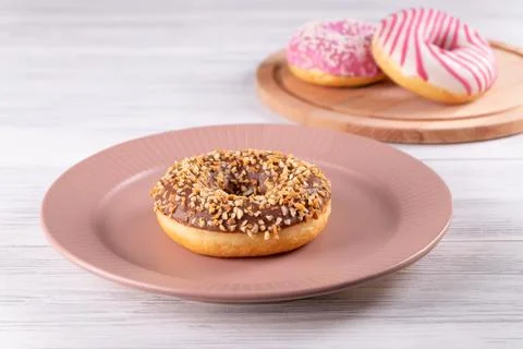 Sugar-coated donuts lie on ceramic plate and wooden cutting board Stock Photos