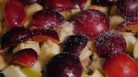 Sugar crystals fall on the sliced fruit. Fruit pie with apple and plum. Stock Footage 239668307