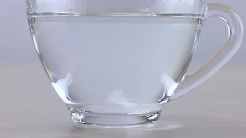 Sugar Cube Dissolving in a Glass Cup of Water Stock Footage 341854204