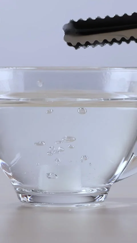 Sugar Cube Dropped into Glass Cup of Hot Water with Tongs Stock Footage 342582361