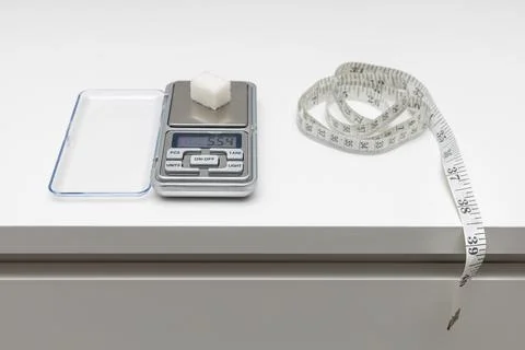 A sugar cube lies on a small scale. Stock Photos