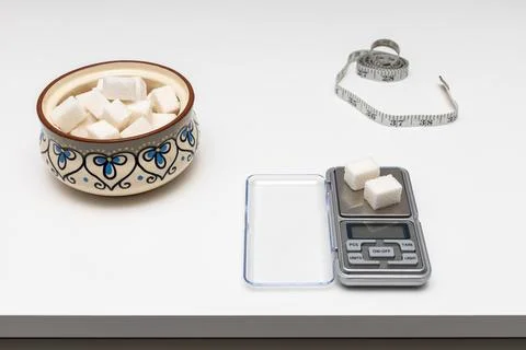 A sugar cube lies on a small scale. Stock Photos