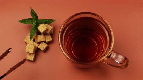 Sugar cubes added into tea glass on brown background Stock Footage 65052649