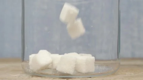 Sugar cubes elegantly falling into a jar, creating a delightful and appealing Video stock 288693421