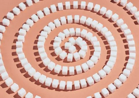 Sugar cubes forming spiral pattern on peach background 스톡 사진