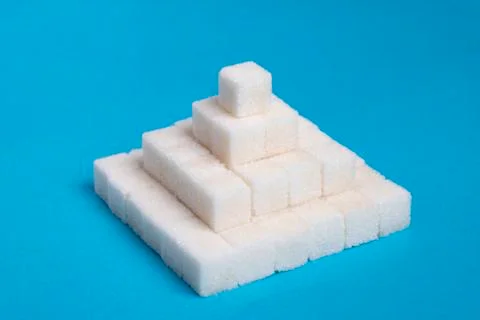 Sugar cubes pyramid on a blue background, creative food idea Stock Photos