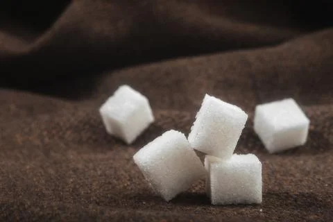 Sugar Cubes Scattered on Brown Fabric Background Foto stock