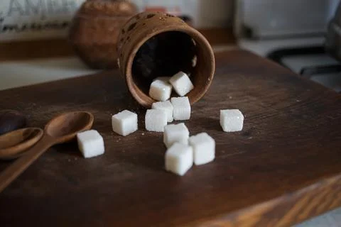 Sugar in cubes scattered on the kitchen board Stock Photos