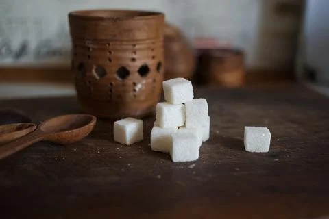 Sugar in cubes scattered on the kitchen board Stock Photos