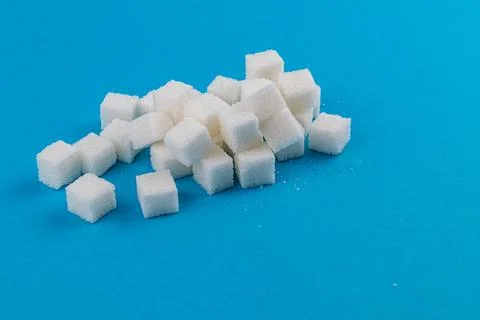 Sugar cubes scattered on a solid blue background creating a visual contrast Foto stock