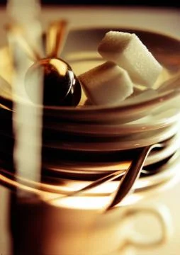 Sugar cubes on stack of saucers and spoons, close-up Stockfoto's